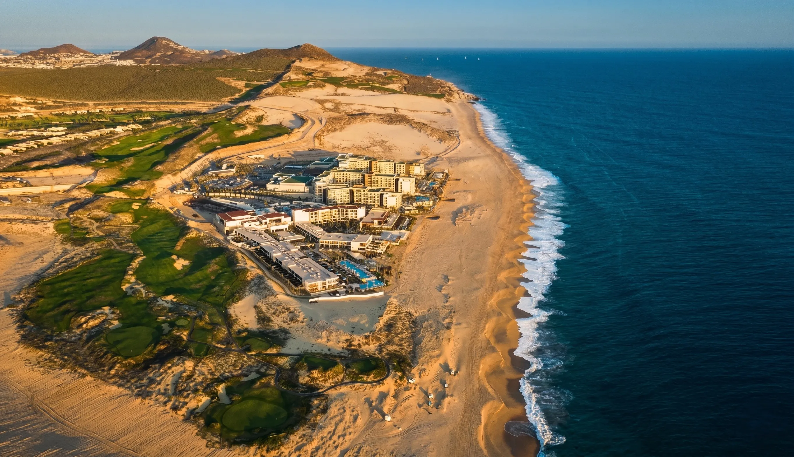 Expansive aerial perspective of the sprawling Diamante luxury golf community and beachfront resort developments stretching along the dramatic Pacific oceanfront.