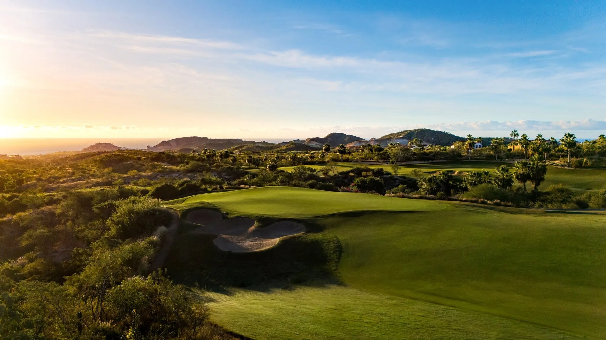 Scenic view of a signature championship golf course hole designed by Tom Fazio at Querencia Los Cabos, highlighting rugged desert arroyos and pristine fairways.