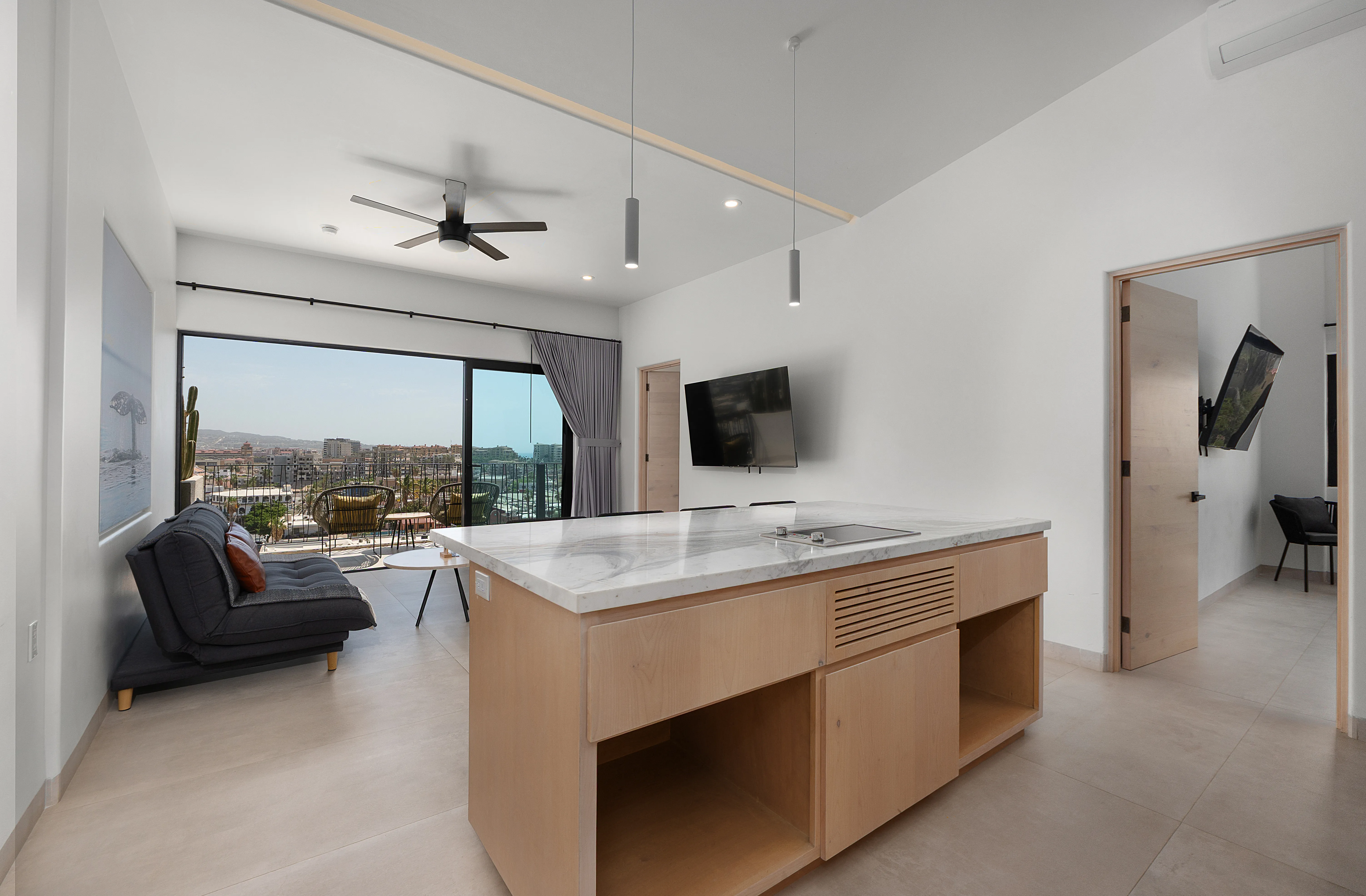 Open-plan luxury interior showing the modern kitchen with a premium marble island and sliding glass doors to the balcony.