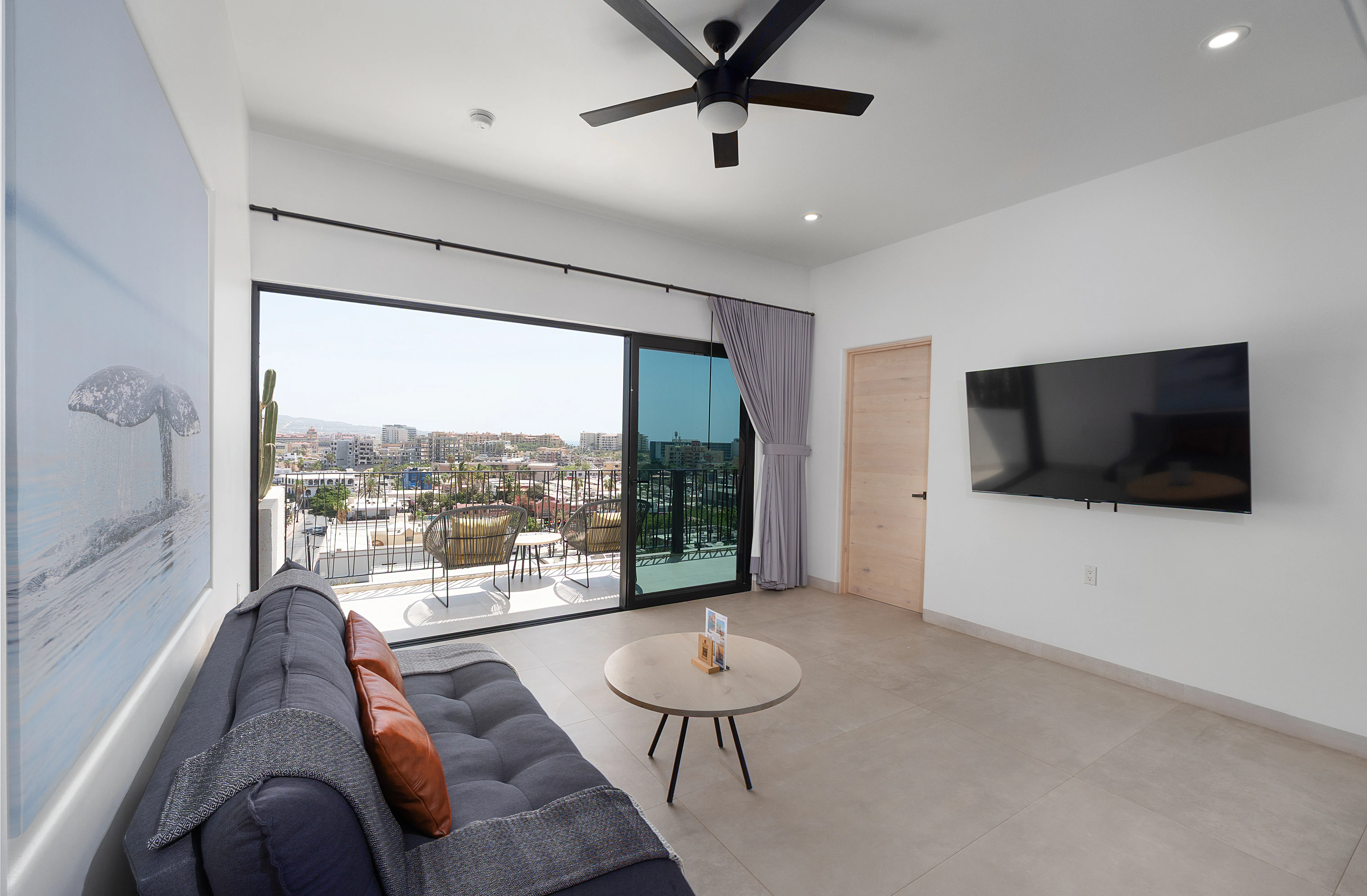 Elegant residential living room displaying a comfortable designer sofa, custom whale artwork, and balcony access.