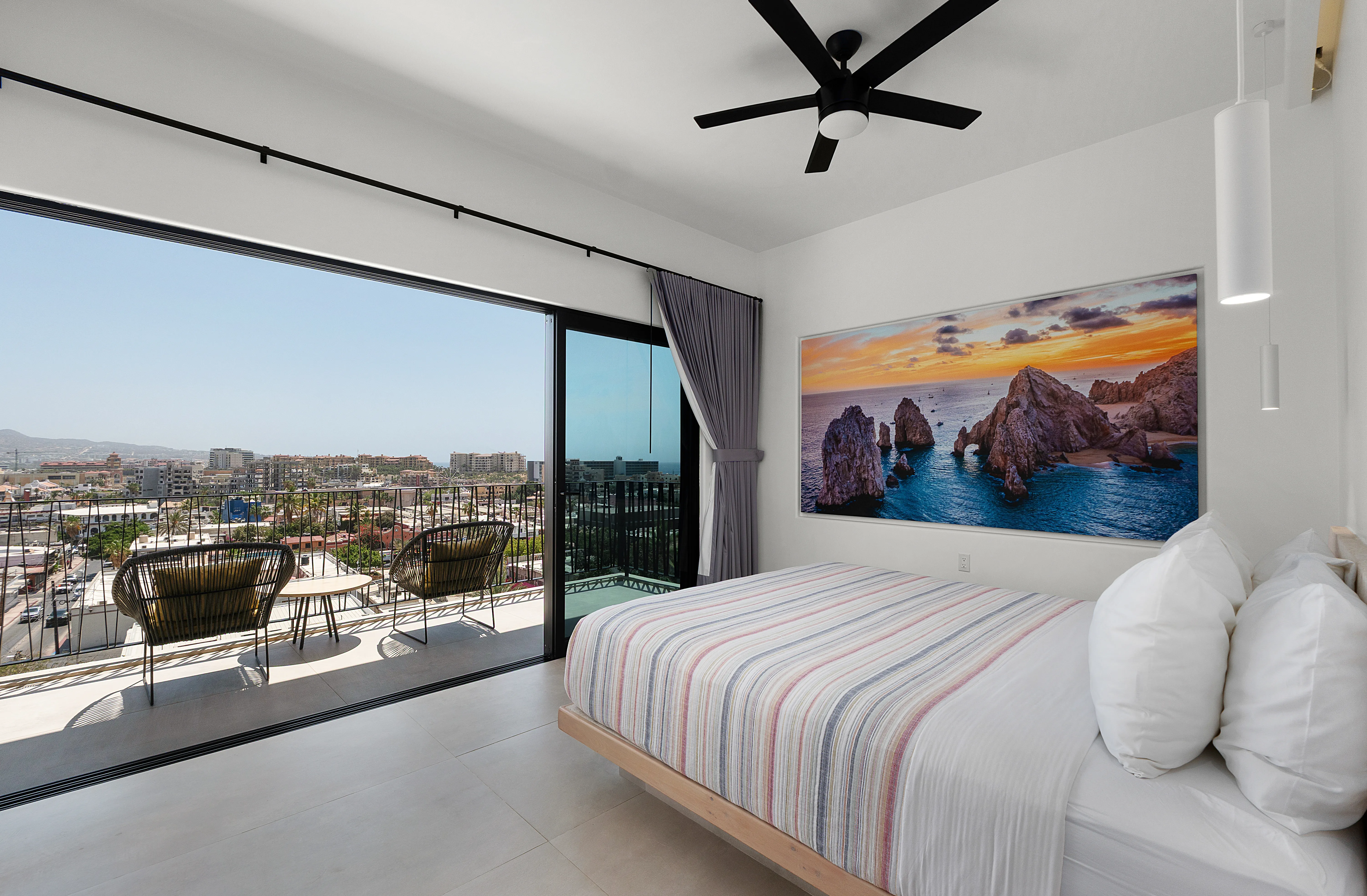 Sophisticated master bedroom suite with a private balcony framing spectacular Land's End El Arco sunset views.