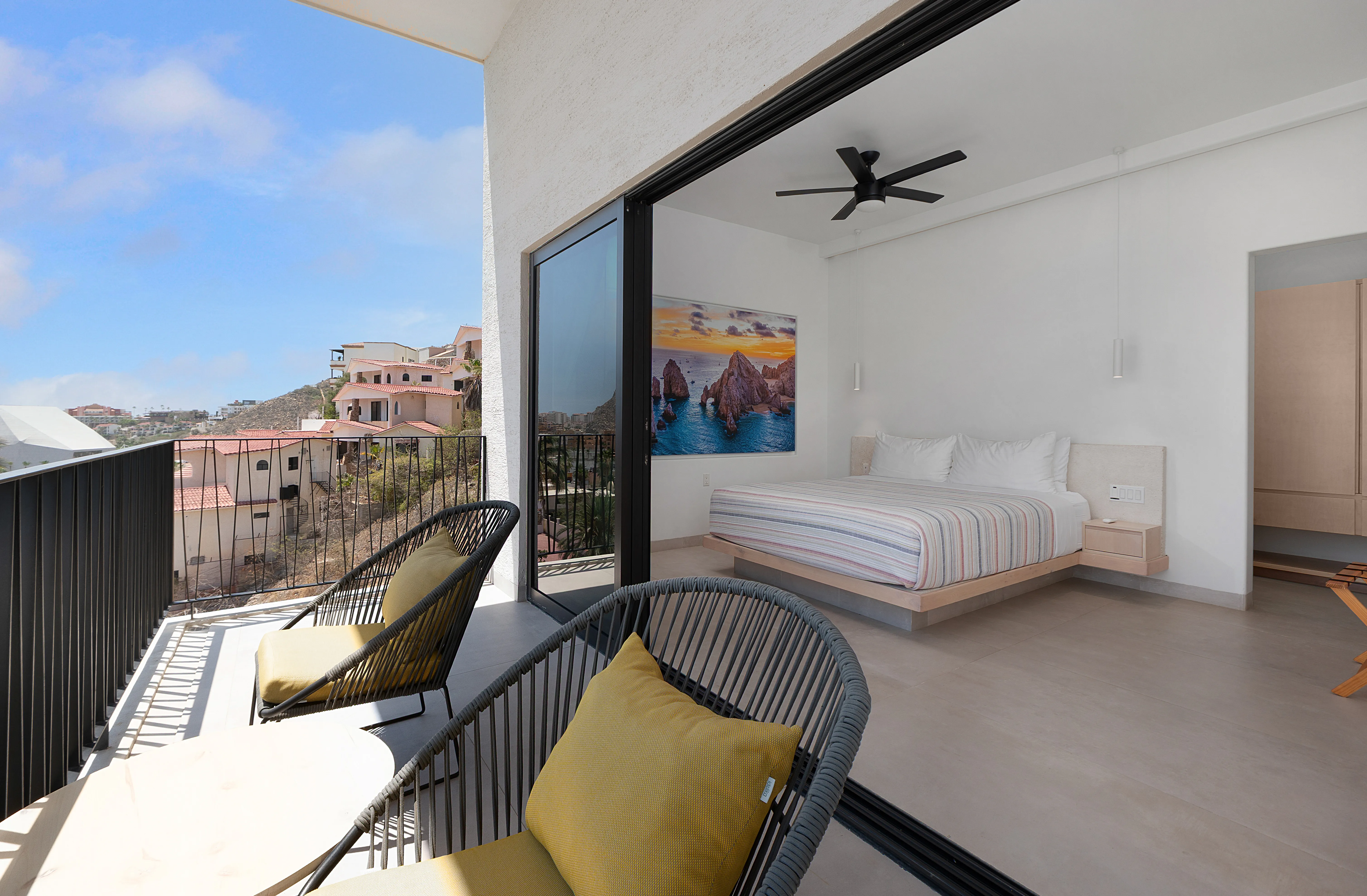 Spacious master suite with an open balcony showcasing unobstructed panoramas of the Pedregal hillside and Cabo skyline.