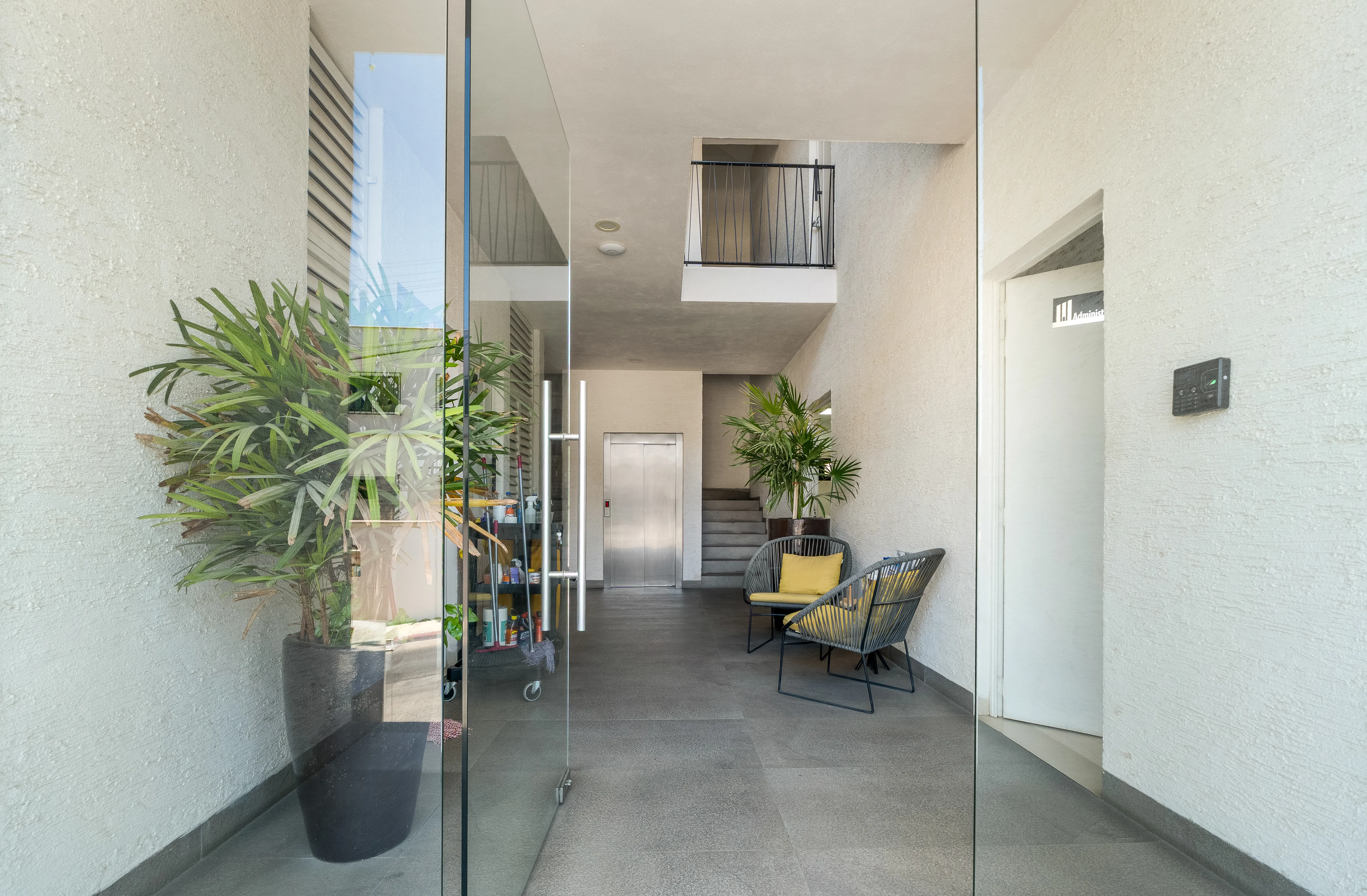 Inviting main residential lobby entrance featuring secure glass doors, elevator bank access, and modern guest seating.