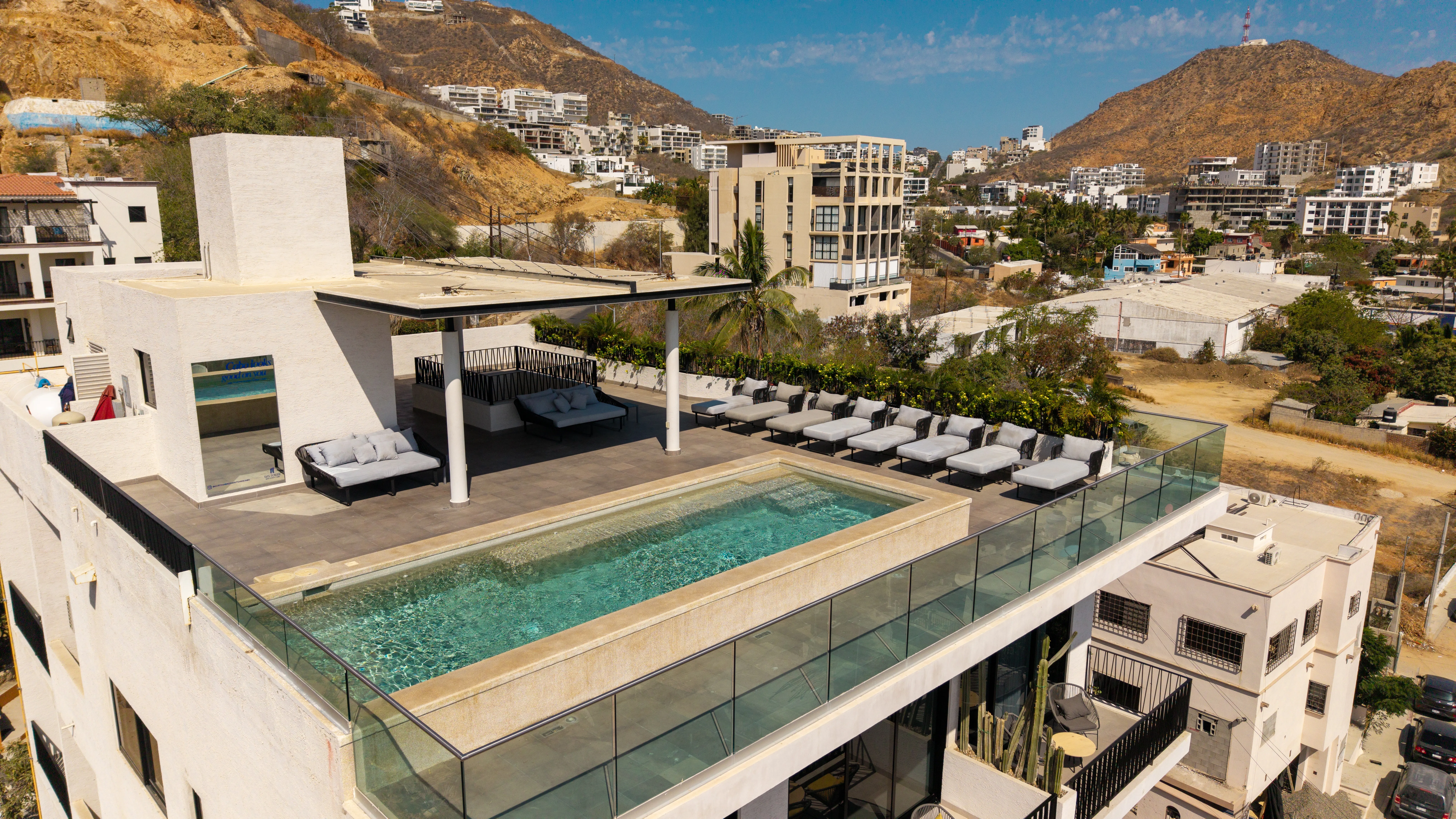 Premium rooftop swimming pool amenity deck with neat rows of sun loungers and comfortable pergola lounges.