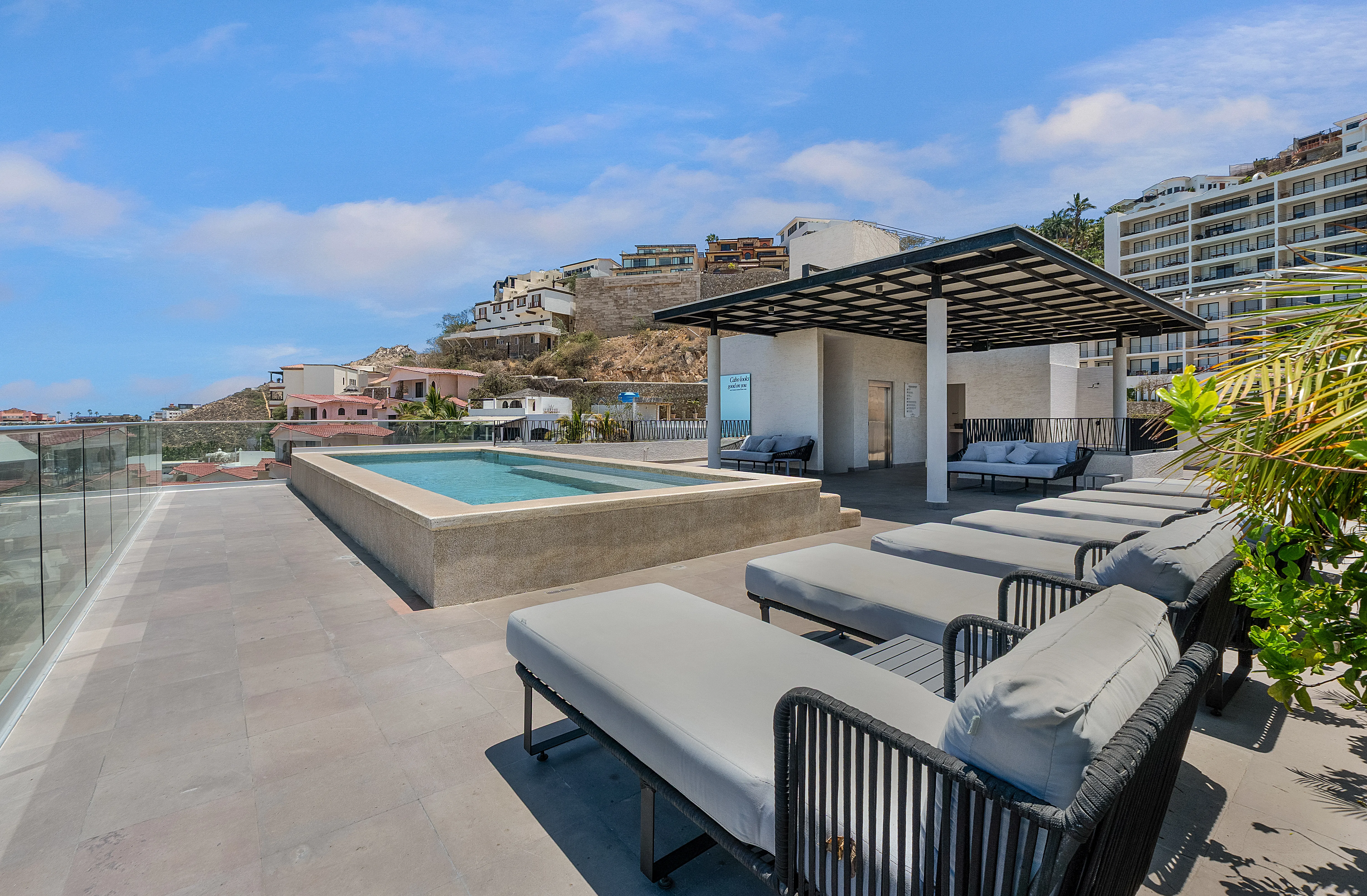 Exclusive rooftop infinity pool deck area capturing picturesque daytime views of the Pedregal hillside community.