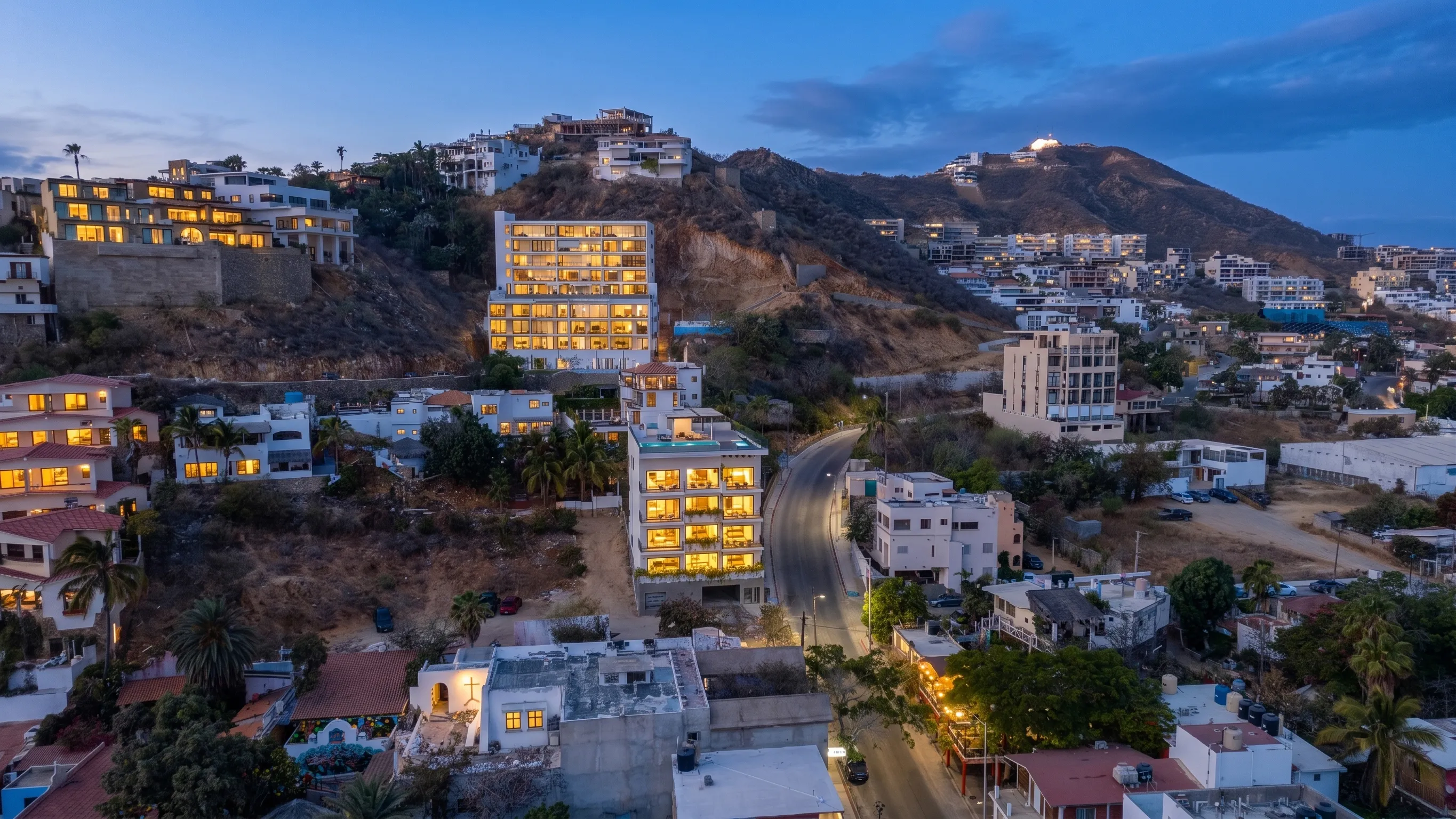 Modern architectural front facade and hillside elevation branding of the 605 Tower studio building in downtown Cabo San Lucas at twilight.