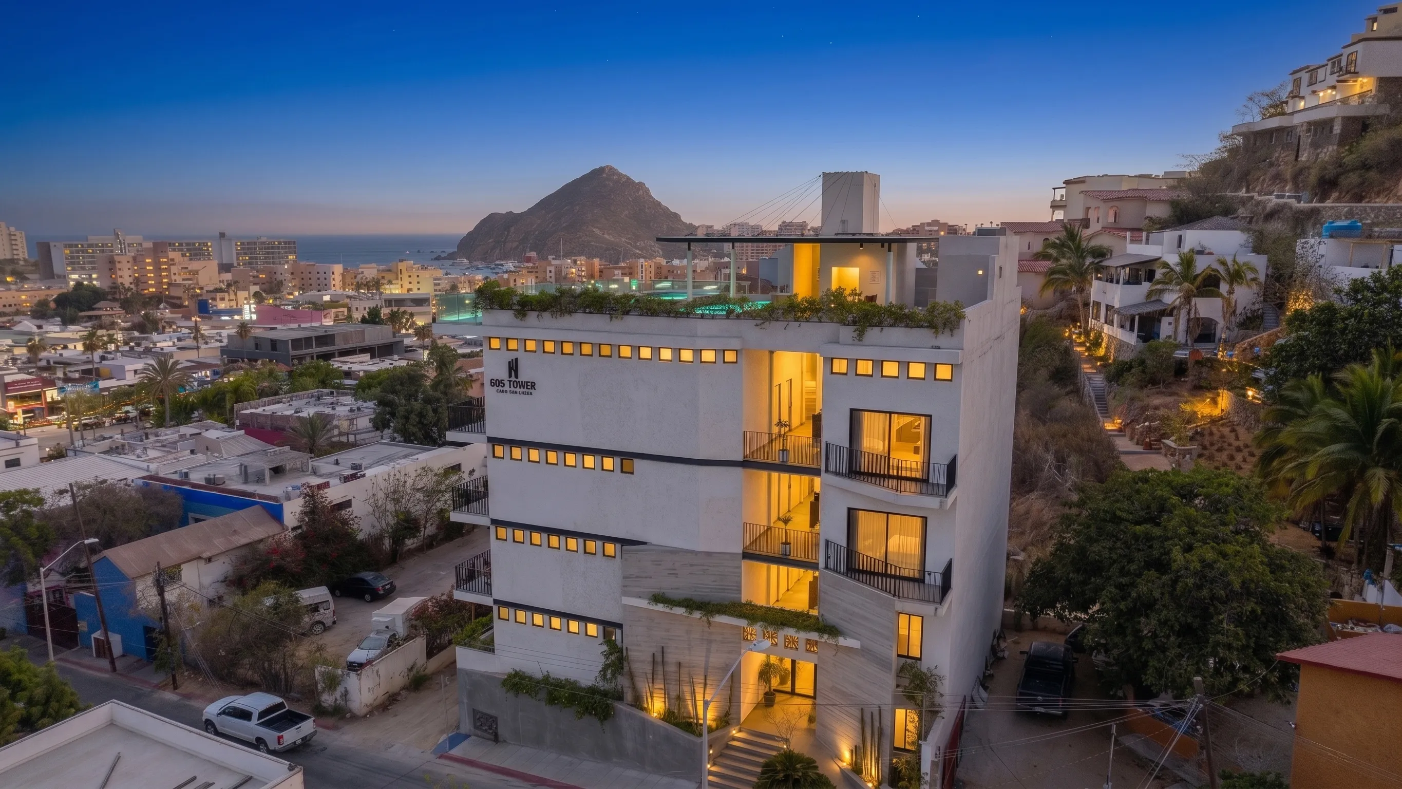 Sleek side facade and modern structural design branding of 605 Tower downtown studio building during blue hour with panoramic marina context.