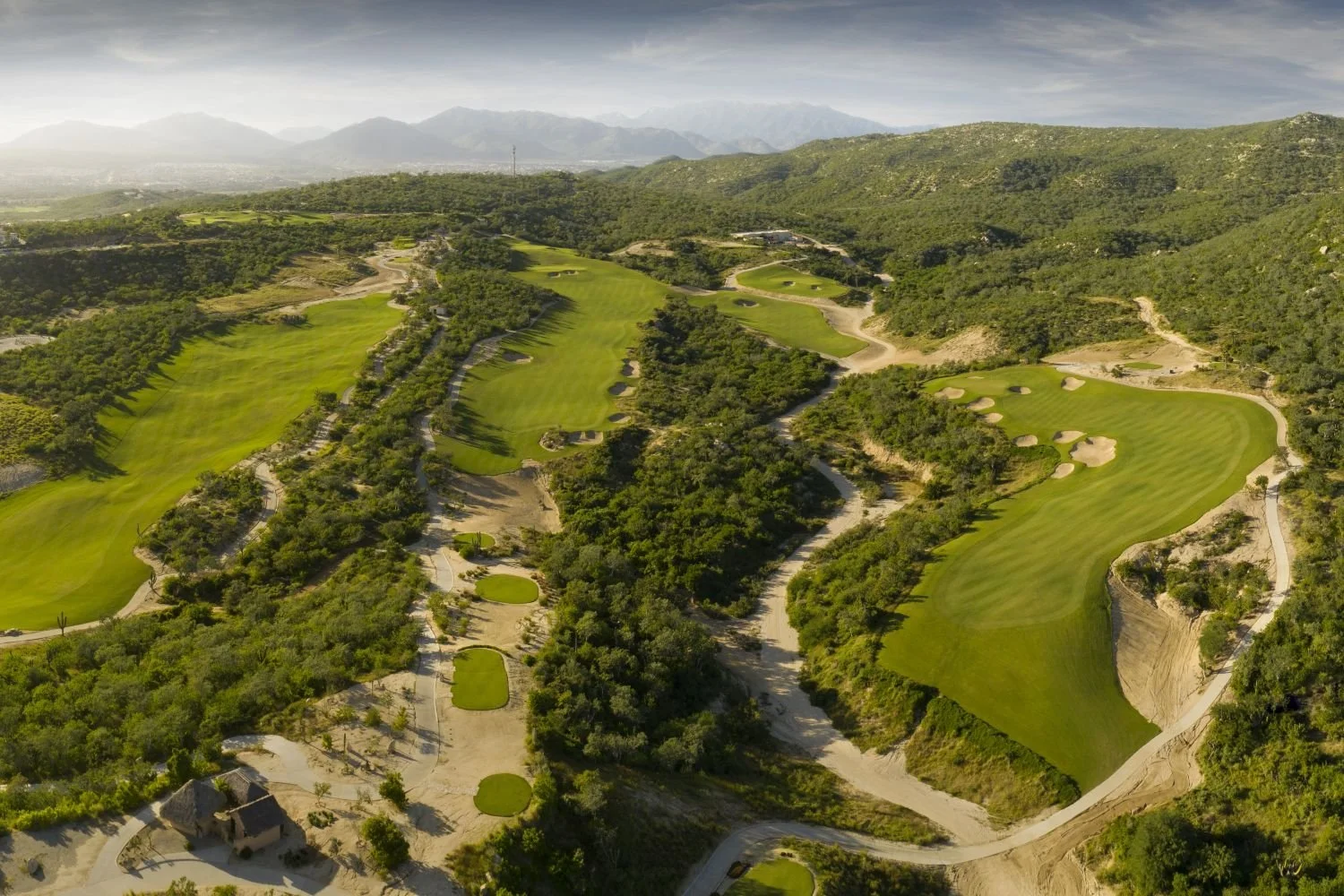 Immaculate green golf fairway integrated into the natural desert terrain and mountain landscape of Puerto Los Cabos.